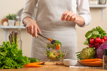 Chef salting fresh and bright salad close-up, on a light background. The concept of losing healthy and wholesome food, detox, vegetarian food, diet, cooking. Slow food, comfort food, clean food