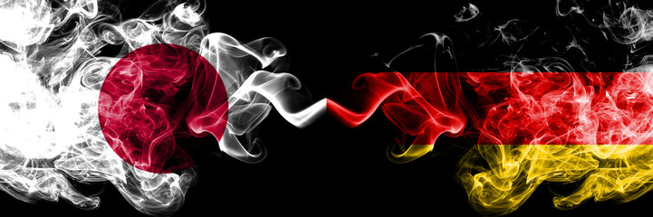 Japan vs Germany, German smoky mystic flags placed side by side. Thick colored silky smokes combination of Germany, German and Japanese flag