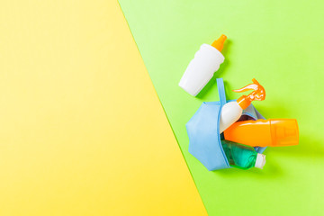 Top view of female cosmetics bag full of suncream spray, sunsreen, sunblock and body lotion and spf cream on yellow and green background with copy space. Directly above. Bright summer concept