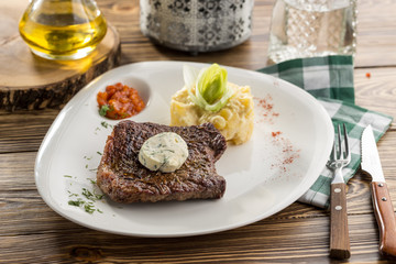 Steak with mashed potatoes and tomato sauce on wooden table