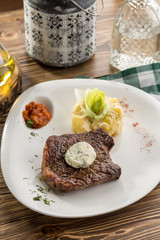 Steak with mashed potatoes and tomato sauce on wooden table