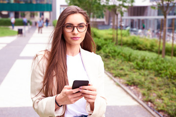 Young businesswoman text messaging while walking on the street in the city