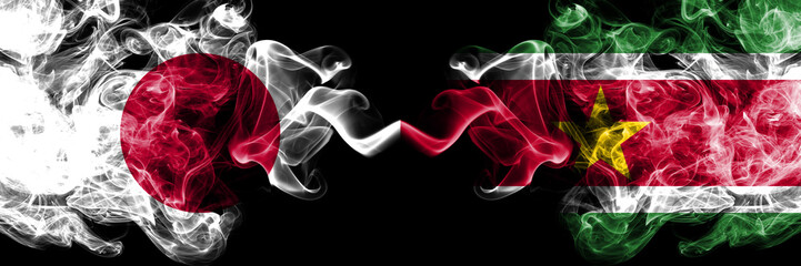 Japan vs Suriname, Surinamese smoky mystic flags placed side by side. Thick colored silky smokes combination of Suriname, Surinamese and Japanese flag