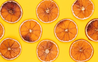 Baked orange slices. Pattern of dried orange slices on yellow background. Creative minimal holiday background.