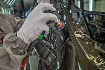 A worker in the painting shop of a car body, sanding painted items