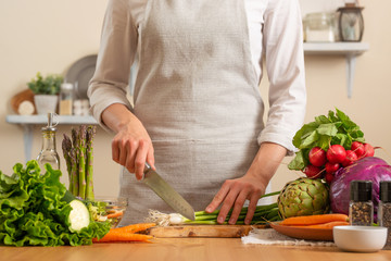 The chef cuts green onions, on a light background. The concept of losing healthy and healthy food, detox, vegetarians, diet, cooking. Slow food, comfort food, healthy diet, clean eating.