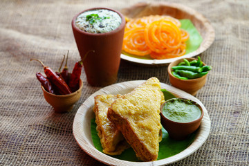 Sandwich Bread Pakora / pakoda (triangle shape) served with tomato ketchup, chutney, green chilli and onion slices, Popular indian tea-time snack