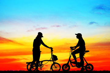 Silhouette group friend  and bike relaxing on blurry sunset background.