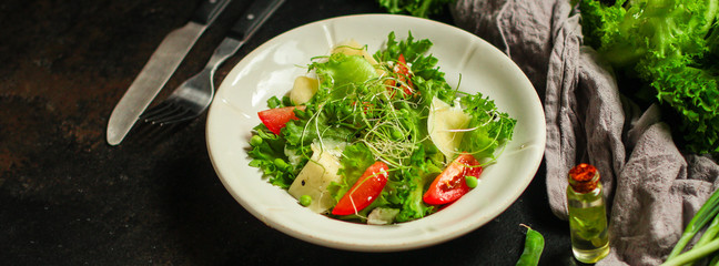 salad with tomato, lettuce, arugula and other green leaves. food background. top