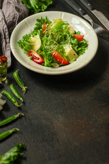 salad with tomato, lettuce, arugula and other green leaves. food background. top