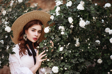 Outdoor close up portrait of young beautiful lady wearing wide brim ribbon tie straw hat, pearl...