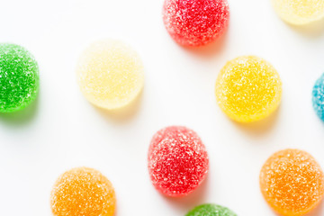 Colorful yellow red orange green gummy jelly candies coated with sugar arranged in pattern on white...