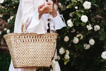 Street fashion details of elegant, trendy summer, spring outfit: straw wicker basket bag in woman`s...