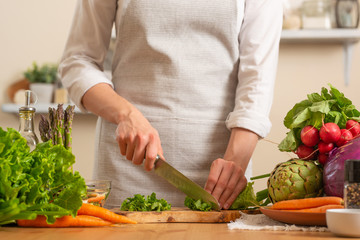 Chef cuts fresh green salad. The concept of losing healthy and wholesome food, detox, vegan eating, diet, cooking. Slow food, comfort food, clean food