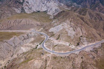 Aerial view of the winding asphalt road paved in the Altai Mountains through rocks with lots of stones, on a clear summer day. Travel in the mountains.