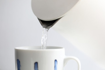 Boiling water trickling in white cup from kettle