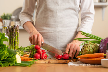 Chef cuts fresh radish for salad. The concept of losing healthy and wholesome food, detox, vegan eating, diet, cooking. Slow food, comfort food, healthy diet, clean eating, horizontal photo