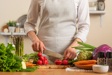 Chef cuts fresh radish for salad. The concept of losing healthy and wholesome food, detox, vegan eating, diet, cooking. Slow food, comfort food, healthy diet, clean eating, horizontal photo