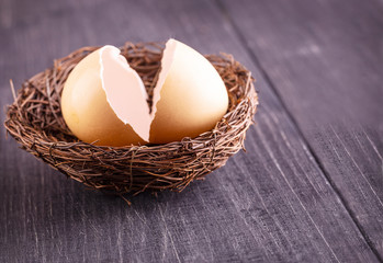 The  broken egg shells in the nest on the old wooden background.