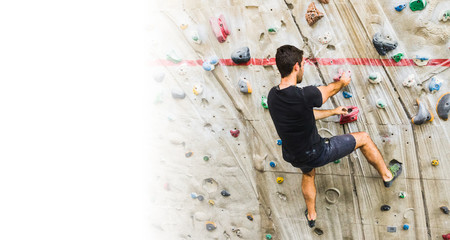 Man practicing rock climbing on artificial wall indoors. Active lifestyle and bouldering concept with copy space.