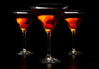 Group of three manhattan cocktails in bar on black table