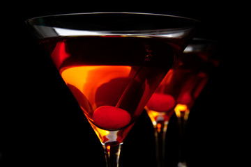 Close-up manhattan drinks with red cherry on black table
