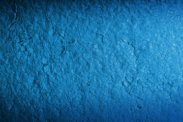 Color blue background of dirty porous material. Illuminated by a narrow strip of light, with shadows on the edges of the image.