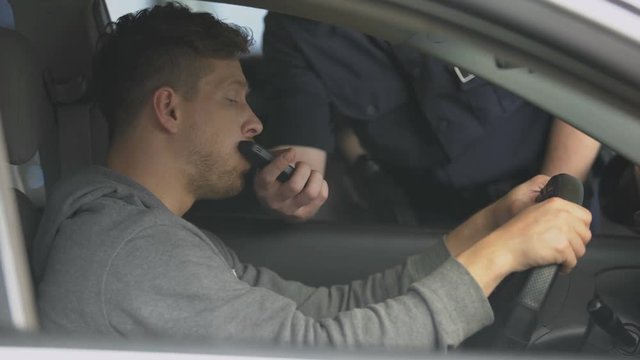 Police officer giving alcohol detection device to young male driver, control
