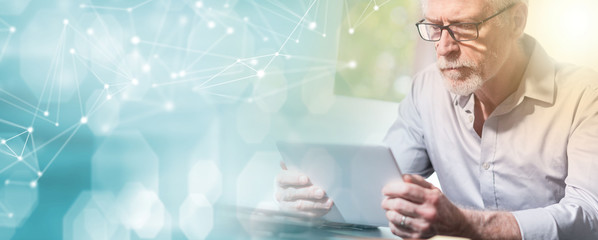 Senior businessman using a digital tablet, light effect; multiple exposure