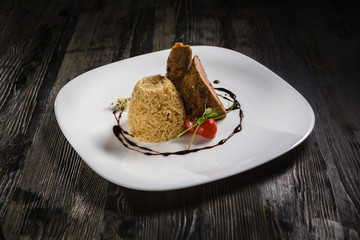 Low key restaurant menu food photo. Delicious fresh rice with meat in white plate on a dark rustic wooden background