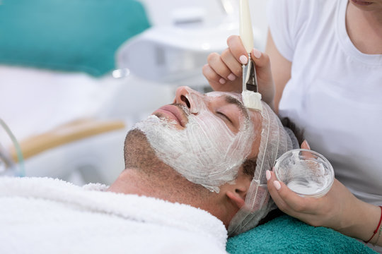Hydration facial mask of man in spa salon. Face massage.