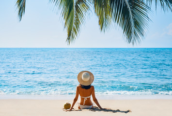Back view of young woman relax alone on tropical beach