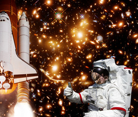 Astronaut gives thumbs-up, rocket and galaxy on the backdrop. The elements of this image furnished by NASA.
