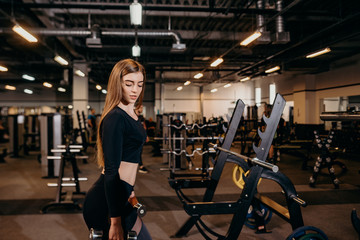 Sports life. Beautiful caucasian woman lifting weights dumbbell for her chest at gym inside.