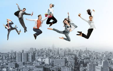 Fototapeta na wymiar Happy office workers jumping and dancing in casual clothes or suit with folders above the city. Ballet dancers. Business, start-up, working open-space, motion and action concept. Creative collage.