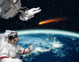 Astronaut gives thumbs-up, comet on the background. The elements of this image furnished by NASA.