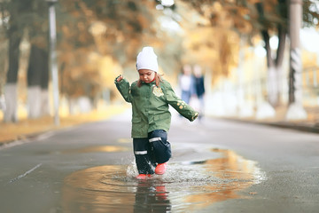 girl runs around the puddles in the autumn park, childhood game