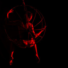 silhouette of sexy woman in red light on a dark background. leggy woman in a bodysuit with metal rings. free space for text
