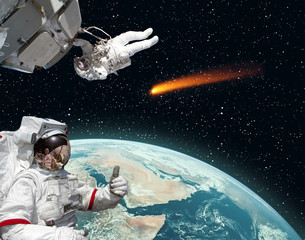 Astronaut gives thumbs-up, comet on the background. The elements of this image furnished by NASA.