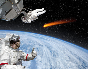 Astronaut gives thumbs-up, comet on the background. The elements of this image furnished by NASA.