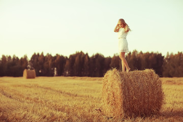 sexy girl in a hay in the field / beautiful young girl posing on a golden hay in the field, summer vacation © kichigin19