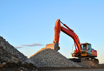Large tracked excavator works in a gravel pit. Loading of stone and rubble for its processing at a...