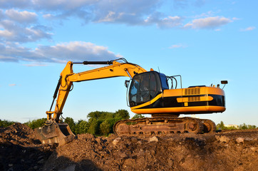 Obraz premium Large tracked excavator digs the ground for the foundation and construction of a new building in the city. Road repair, asphalt replacement, renovating a section of a highway, bridge construction