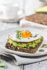 Sandwich with avocado, egg and spinach on white wooden background. Healthy diet breakfast