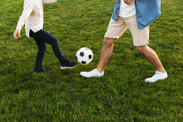 Two cheerful brothers playing football on the lawn