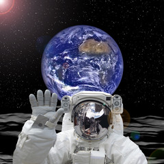 Astronaut posing on alien land. Earth on the backdrop. The elements of this image furnished by NASA. © wowinside