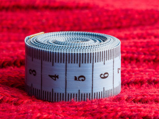 Sewing still life blue tape measure on background of red wool fabric