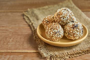 Healthy organic energy granola bites with nuts, cacao, prunes, sesam and honey - vegan and vegetarian raw snack on wooden background
