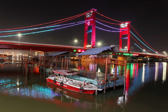 Palembang's Ampera bridge is photographed at night, with natural lighting and slow speed photography techniques.