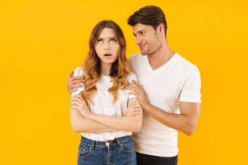 Portrait of handsome man asking for forgiveness irritated woman after fight standing with arms crossed